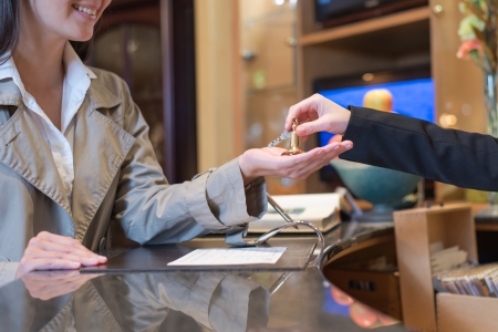 female guest being handed over the keys to hotel room by receptionist, travel and tourism conceptの写真素材
