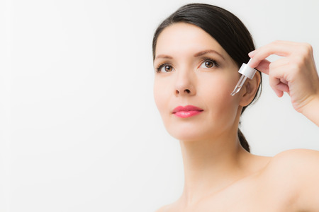 beautiful young woman holding an eye dropper in her handの写真素材