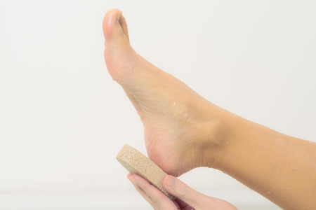Woman relaxing in a hot soapy bath using a pumice stone to exfoliate her feetの写真素材