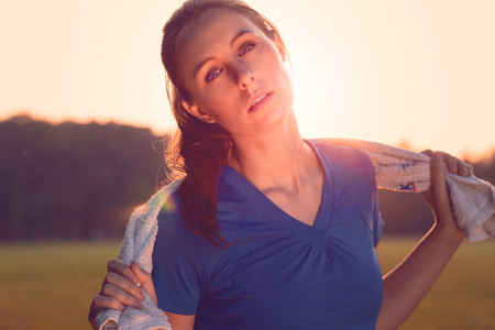 Attractive woman outdoors at sunset backlit by the orange glow of the sun causing a flare around her faceの写真素材