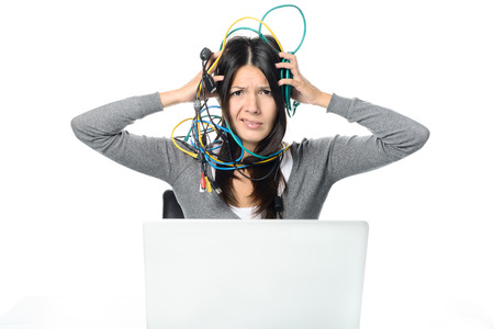Close up Upset Woman in Gray Long Sleeve Shirt Putting Tangled Network Cables on Her Head While Experiencing No Internet Connection to her Laptop. Looking at the Camera. Isolated on White Background.の写真素材