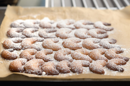 Background of traditional crescent shaped Christmas cookies or biscuits with crisp golden pastry sprinkled with sugar on a kitchen counterの写真素材