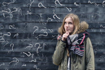 Pretty young female student in class with a problem to solve standing in front of a chalkboard in...