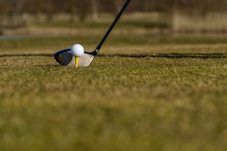 Conceptual image of a golfer teeing-off on the fairway with a low angle view of the ball on a tee...