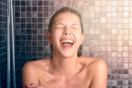 Close up Happy Bare Young Woman Taking Shower at the Bathroom with Mouth Open and Eyes Closed.の写真素材