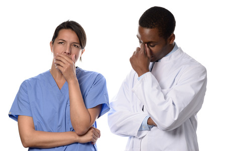 Tired worried doctor and nurse or surgeon in scrubs standing with their hands to their faces and serious expressions after a long operation or procedure as they ponder the outcome, isolated on whiteの写真素材