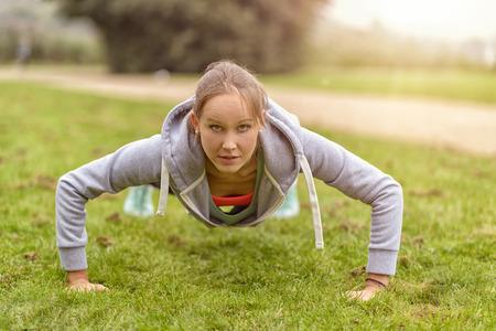 Athletic Young Woman Smiling at the Camera While Doing Push Up Exercise at the Park.