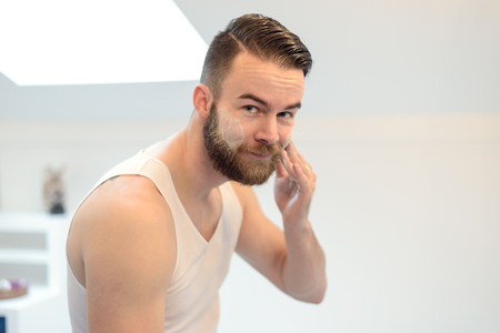 Young man applying shaving cream above his beard, morning routine, a personal care and hygiene conceptの写真素材