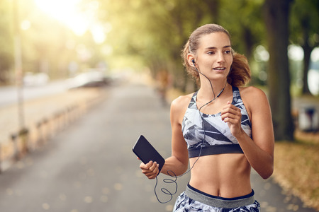 Fit healthy athletic woman jogging on a river bank smiling happily with her long hair flying out...