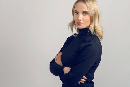Studio portrait of a beautiful young woman with blond hair looking at camera with confident attitude...