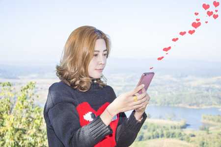 women asia in love use telephone send message to boyfriend valentine day and landscape backgroundの写真素材