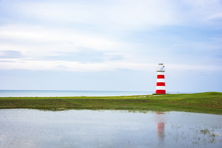 lighthouse on greensward and sky blue near seaの写真素材