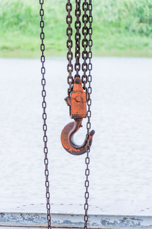 old orange hook and chain near riverの写真素材