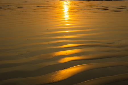 gold sand on the beach silhouette and sun setの写真素材