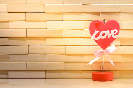 Happy valentine's day concept. Love word and red heart shape on wall made from wooden blocks under sunlight with copy space for wallpaper or backgroundの写真素材