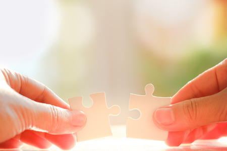 Woman's hand holding and connecting jigsaw puzzles. Business solutions, connection, achievement, and strategy conceptの写真素材