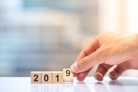 Hand holding wooden block number 9 to complete year 2019 on cityscape background with copy space.の写真素材