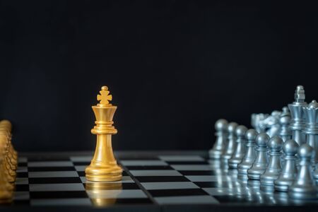 Gold king chess stands on chessboard surrounding with opponents on dark background with copy space. Business strategy, planning, decision making, and competition concept.の写真素材