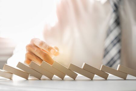Businessman failed from trying stop domino effect of wooden blocks. Business crisis management...