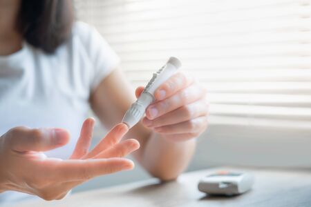 Close up woman hands using lancet on finger to check blood sugar level by Glucose meter, Healthcare Medical Check up, Medicine, diabetes, hyperglycemia conceptの写真素材