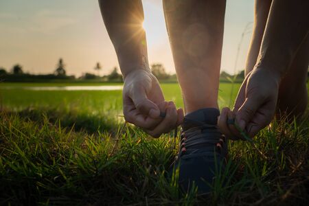 Silhouette young woman tying laces in sunrise.の写真素材