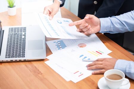 Selective focus on hands of two businessman working on business reports on desk with notebook and...