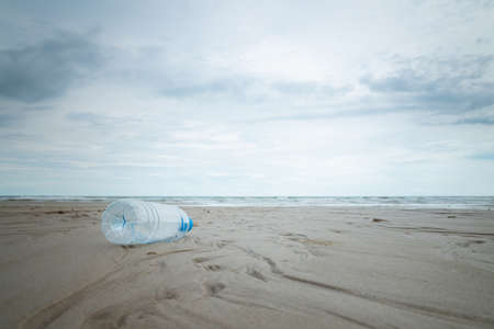 Used plastic bottle on beach with soft wave and cloud in the sky.の写真素材