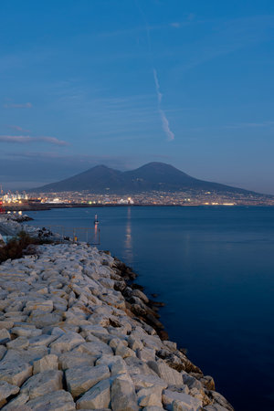 Panoramic view of Naples with cliffs, lights, and a post-sunset atmosphere overlooking Mount Vesuvius and the seaの写真素材
