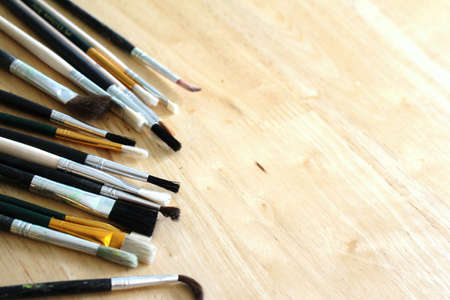 Mixed artists paint brushes on pine table with spaceの写真素材