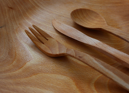 Wooden cutlery on a wooden plateの写真素材