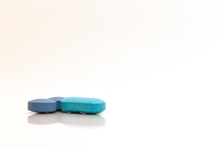 Medications in the form of pills and tablets. Drugs in blue and light blue pills with white background.の写真素材