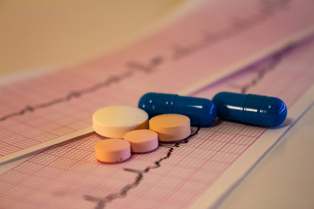 Some colored pills on electrocardiogram strips with heartbeats. Graph paper for recording cardiac activity.の写真素材