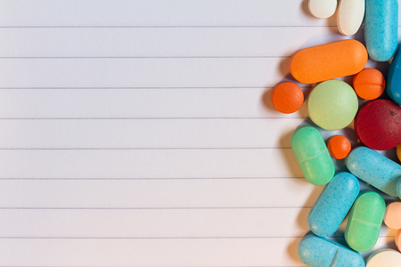 Pills and colored capsules on a neutral striped background. Group of medicines.の写真素材