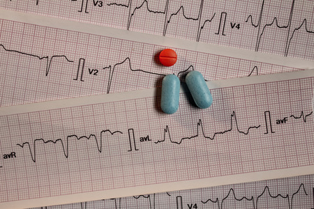 Medications in the form of tablets for oral use on an electrocardiogram background. Heartbeat...