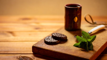Rustic table with some chocolates and mint leaves next to a cup of coffee. Resource for designers.の写真素材