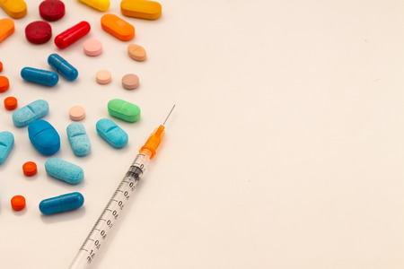Colorful pills on white background. Transparent syringes with your small needle. Medications for...
