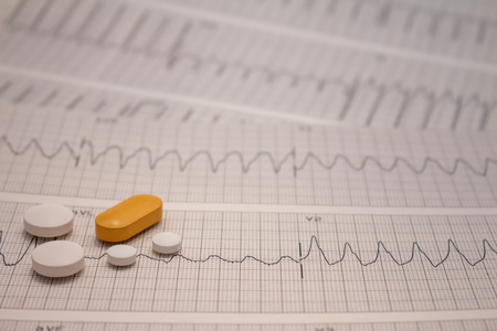 Small pills or legal drugs on strips of electrocardiograms that are out of focus.