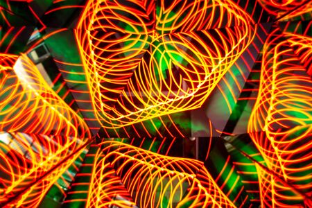 Colored lights in the form of lines that form abstract and symmetrical patterns. Kaleidoscopic effect. Long exposure photography. Reflective mirrors of colorful lights.の写真素材