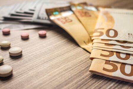 Banknotes and medicines on a desk. Health cost concept. Drugs for legal use and money.の写真素材