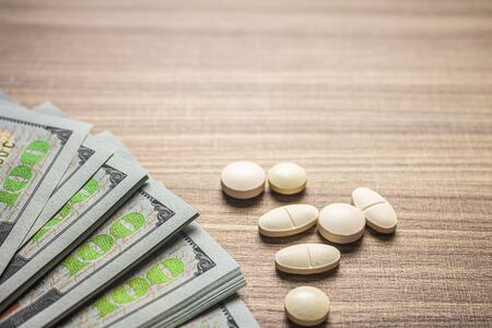 Concept of cost of medicines. Pills on a brown table with bills.の写真素材