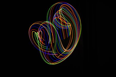 Long exposure photography made with multicolored light paint on black background, waves, curves and...