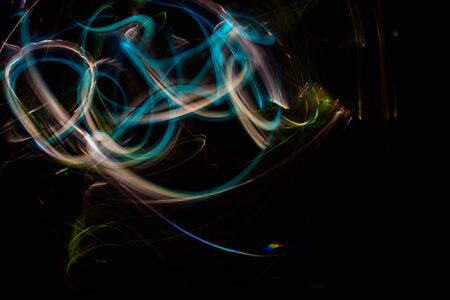 Long exposure photography made with light paint of various colors on a black background, waves, curves and swirls, curvilinear or rounded pattern.の写真素材