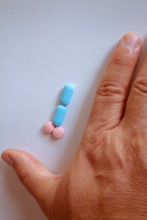 Hands of a man next to pills that symbolize a penis with an erection. Male metaphor. Medicine related to male impotence. Virility concept.の写真素材