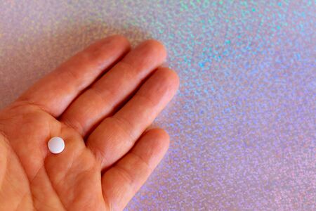 A man's hand holding a pill on a festive litmus colored background. Drug for impotence. Medicines for sex.の写真素材
