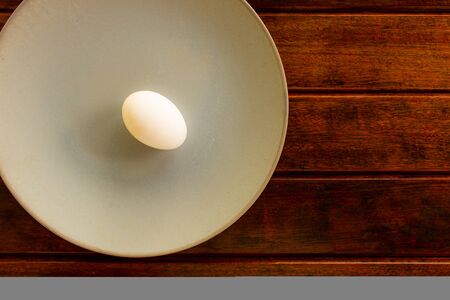 A chicken egg on a plate and a wooden table. Copy Space Organic and natural food. Vegetarian food.の写真素材