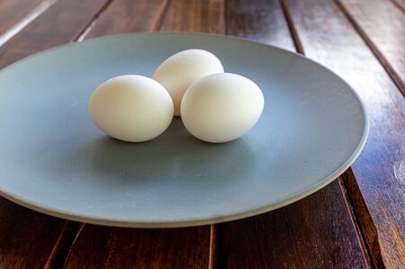 Chicken eggs on a plate and a wooden table. Copy Space Organic and natural food. Vegetarian food.の写真素材
