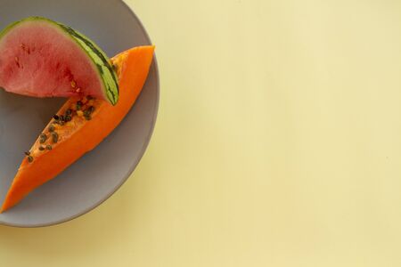 Tropical fruits on a neutral plate. Free space to write. Natural food for breakfast.