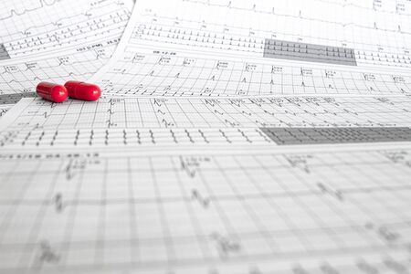 Two red capsules on electrocardiograms. Cardiovascular disease concept. Heartbeats represented on paper. EKG Backgroundの写真素材