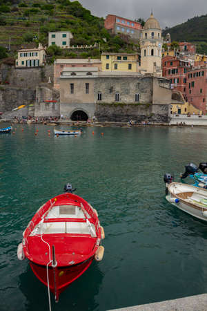 Cinque Terre, Italy. May 15, 2018. Picturesque town in northern Italy. Boats moored at the dock next to the Cathedral. Tourist town.のeditorial素材