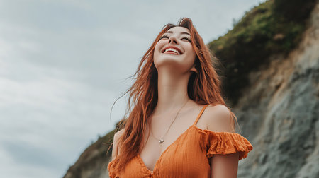 beautiful young asian woman in orange dress standing on cliff and smilingの素材